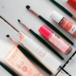 Flatlay image showcasing various makeup products and brushes arranged on a white surface, ideal for beauty themes.