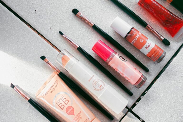 Flatlay image showcasing various makeup products and brushes arranged on a white surface, ideal for beauty themes.