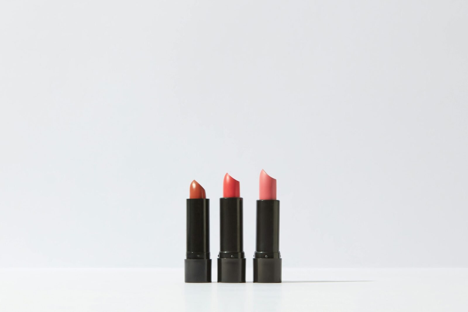A minimalist display of three lipsticks on a white background, perfect for cosmetic themes.