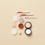 A flat lay of makeup brushes and cosmetics on a beige background, perfect for beauty themes.