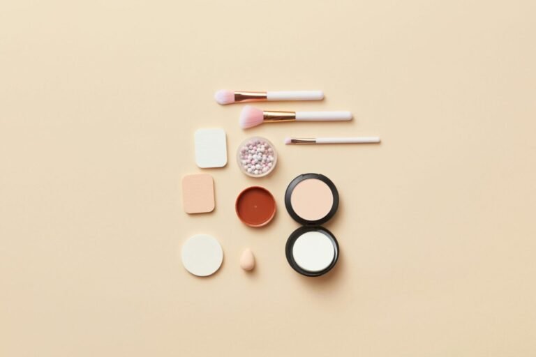 A flat lay of makeup brushes and cosmetics on a beige background, perfect for beauty themes.